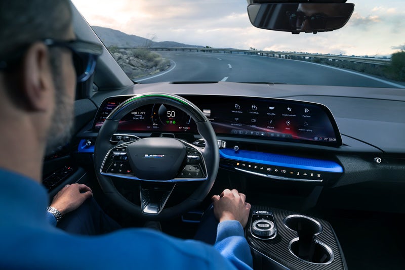 Front View of the 2026 OPTIQ-V Driving Through the Dusk Utilizing its Headlights | Plaza Cadillac in Leesburg FL