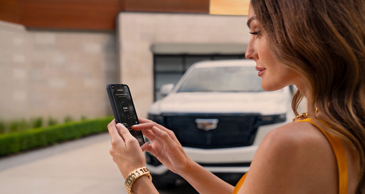 lady checking her mobile with a Cadillac vehicle background | Plaza Cadillac in Leesburg FL